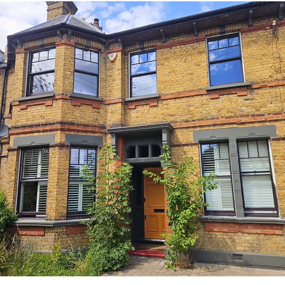 Finished grey-painted sashes and timber door on a yellow-brick London house